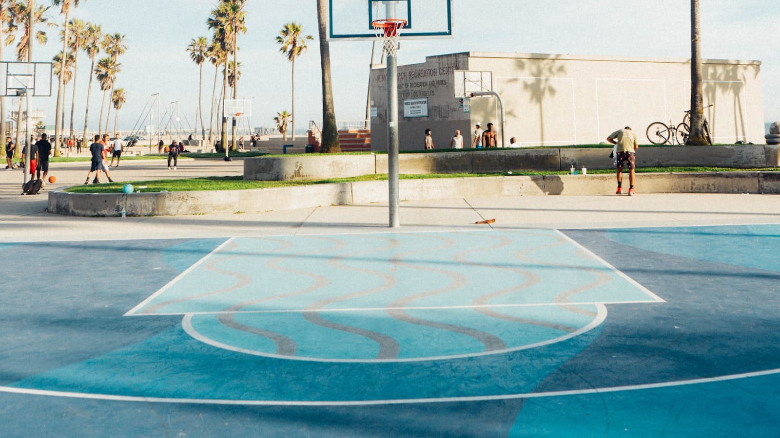 People gathered at an outdoor city basketball court for a pickup game